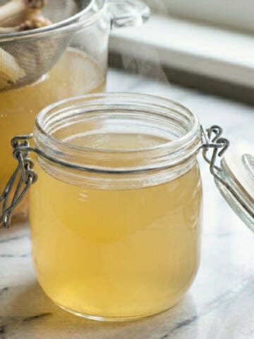 Chicken stock in a jar on a marble surface.