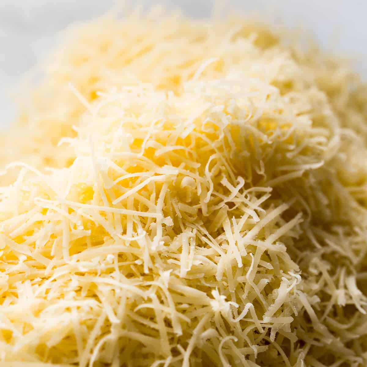 Finely grated Parmigiano-Reggiano cheese being mixed into the sandy flour and butter mixture.
