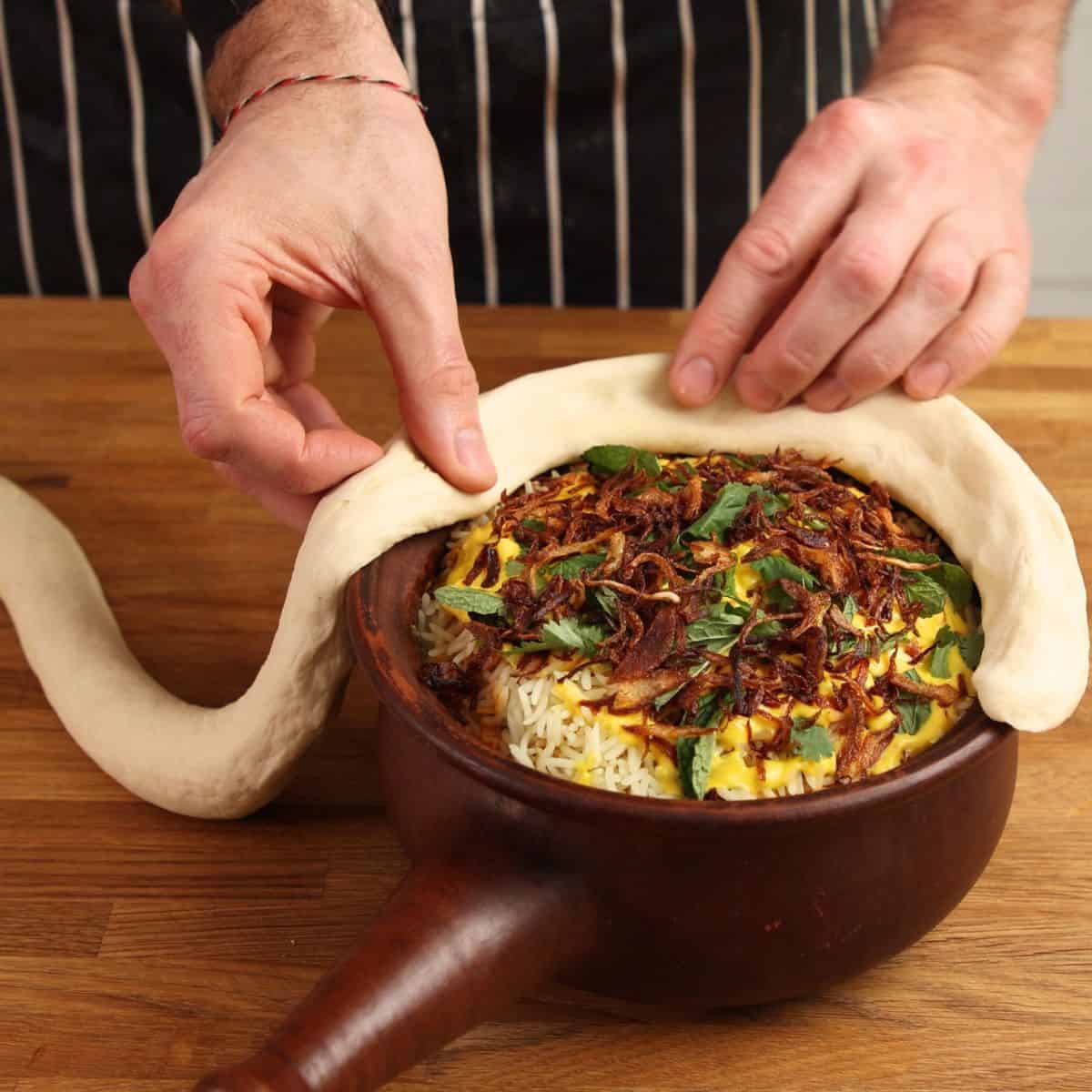 Sealing dough around clay pot.