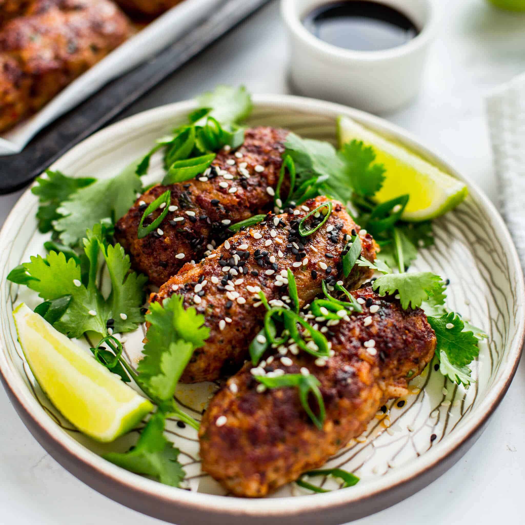 Thai spiced beef koftas with sesame, spring onion, soy and lime on white plate