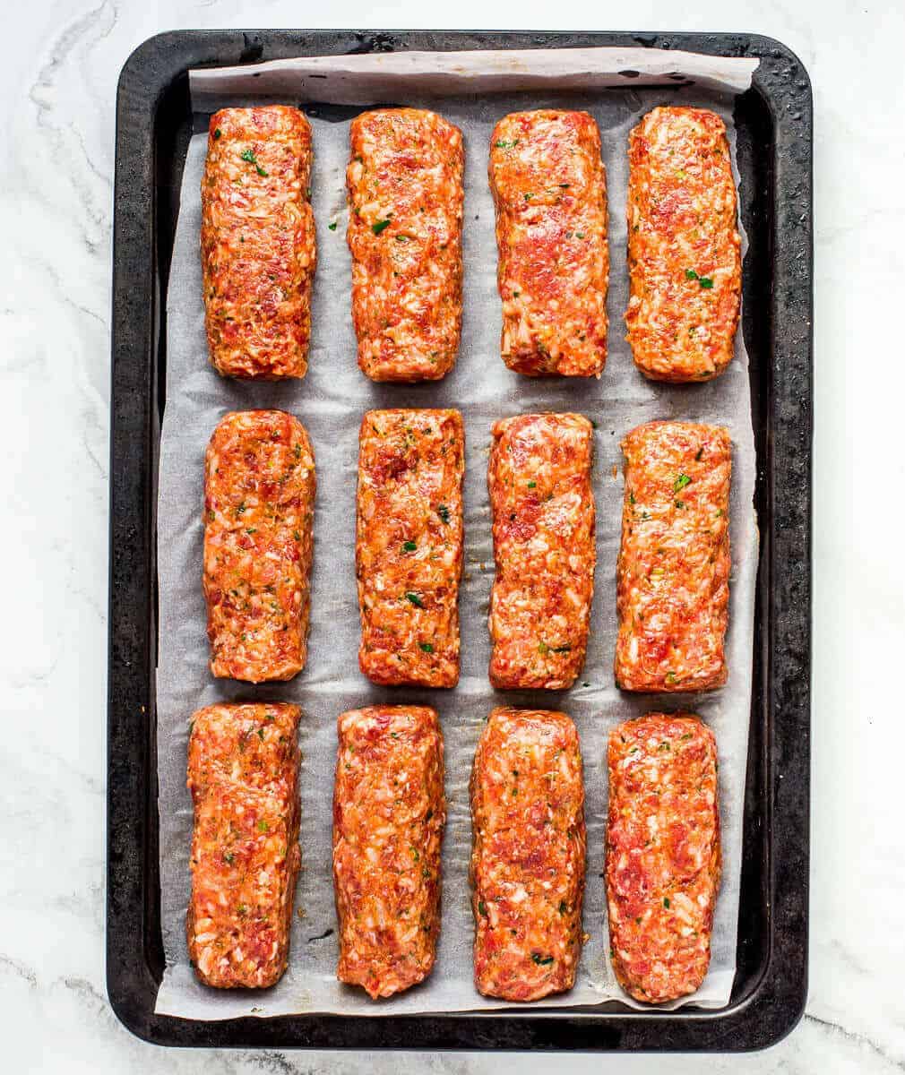 raw koftas shaped on a white piece of parchment.