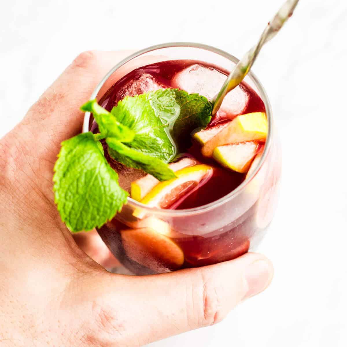 hand holding a red sangria in a glass