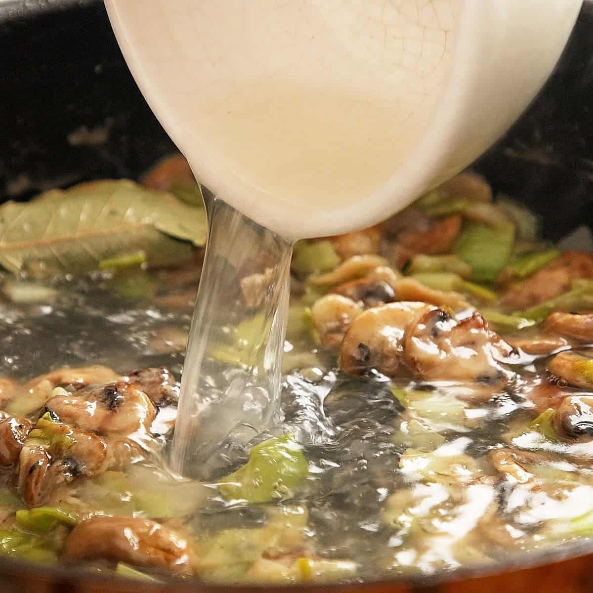 Adding chicken stock to make velouté for chicken fricassee.