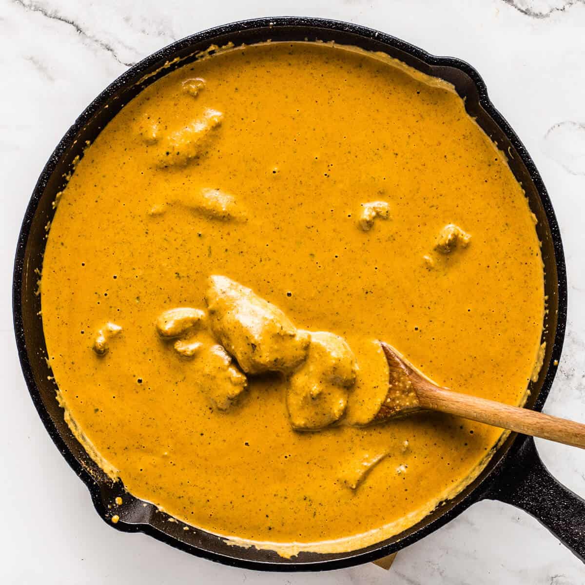 Finished butter chicken curry with chicken pieces simmering in sauce.