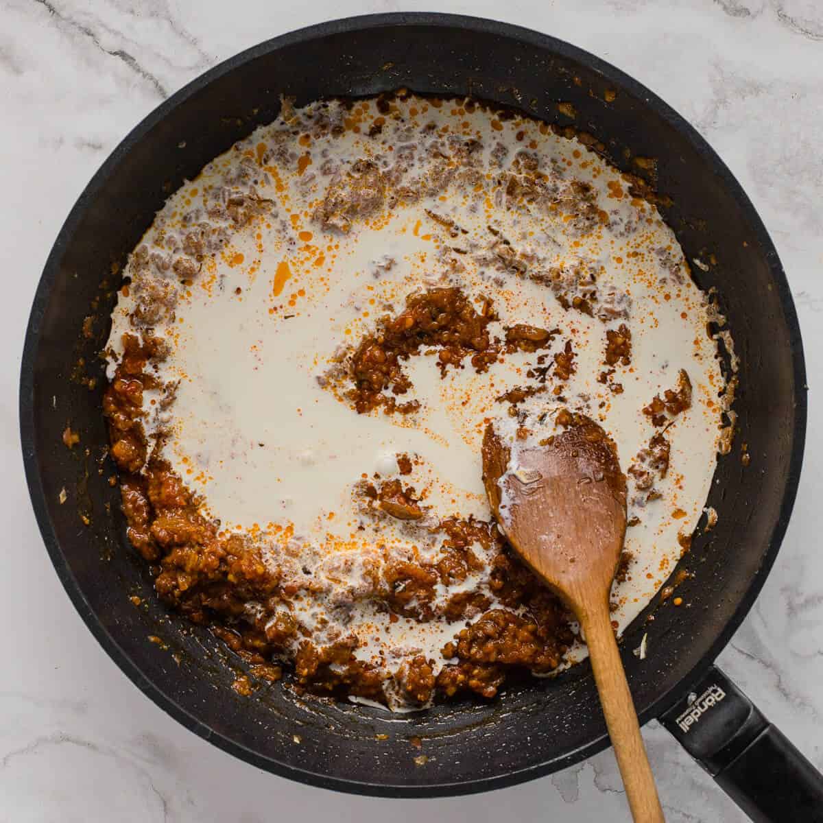 Cream stirred into rich tomato and spice base.