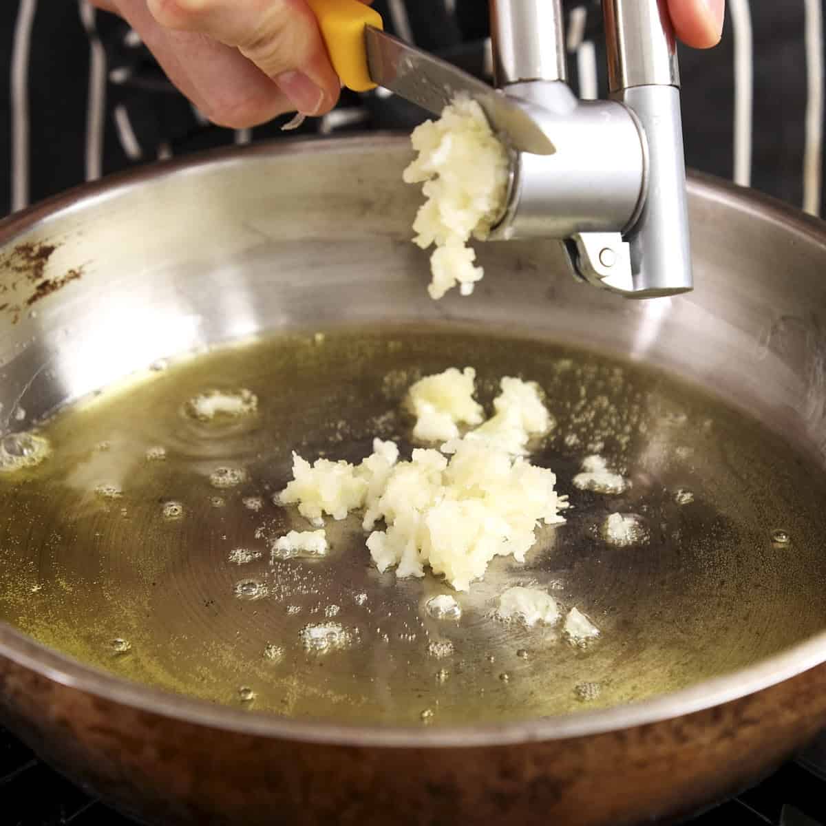 Adding crushed garlic to melted ghee.