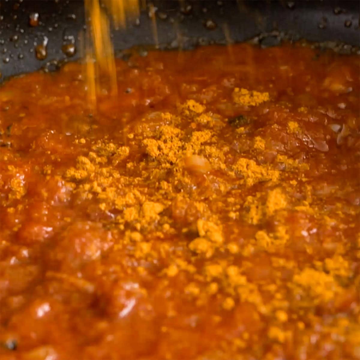 Adding curry powder to curry.