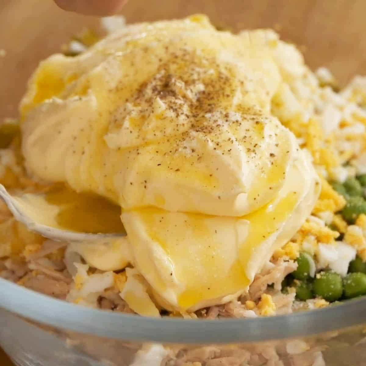 Adding mayonnaise and seasoning to salad.
