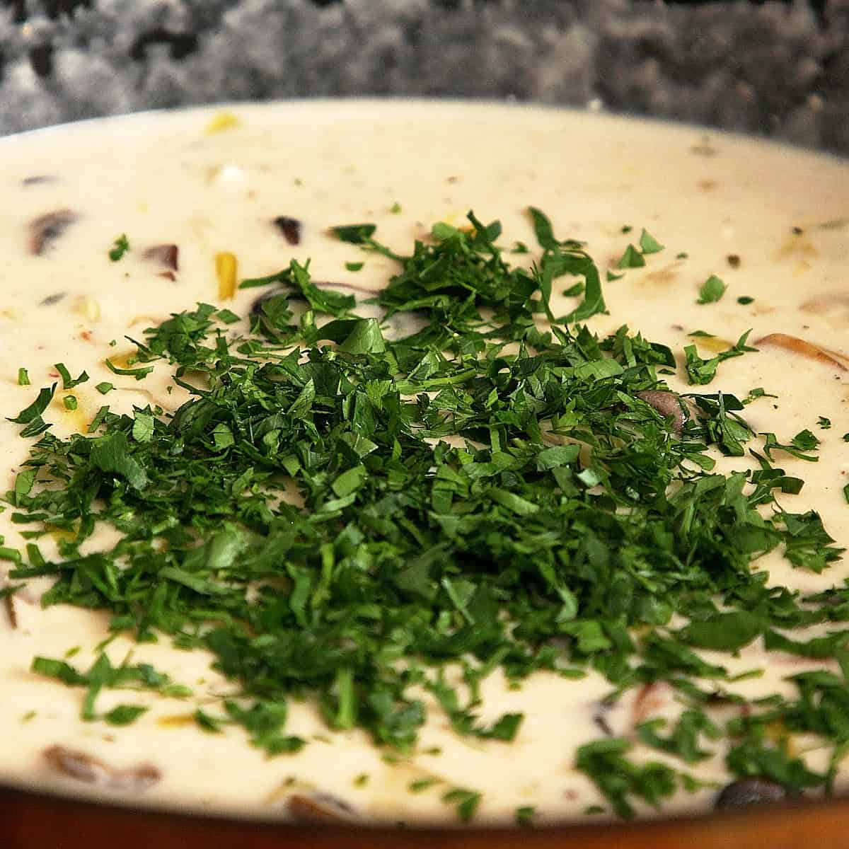 Adding chopped parsley to cream sauce.