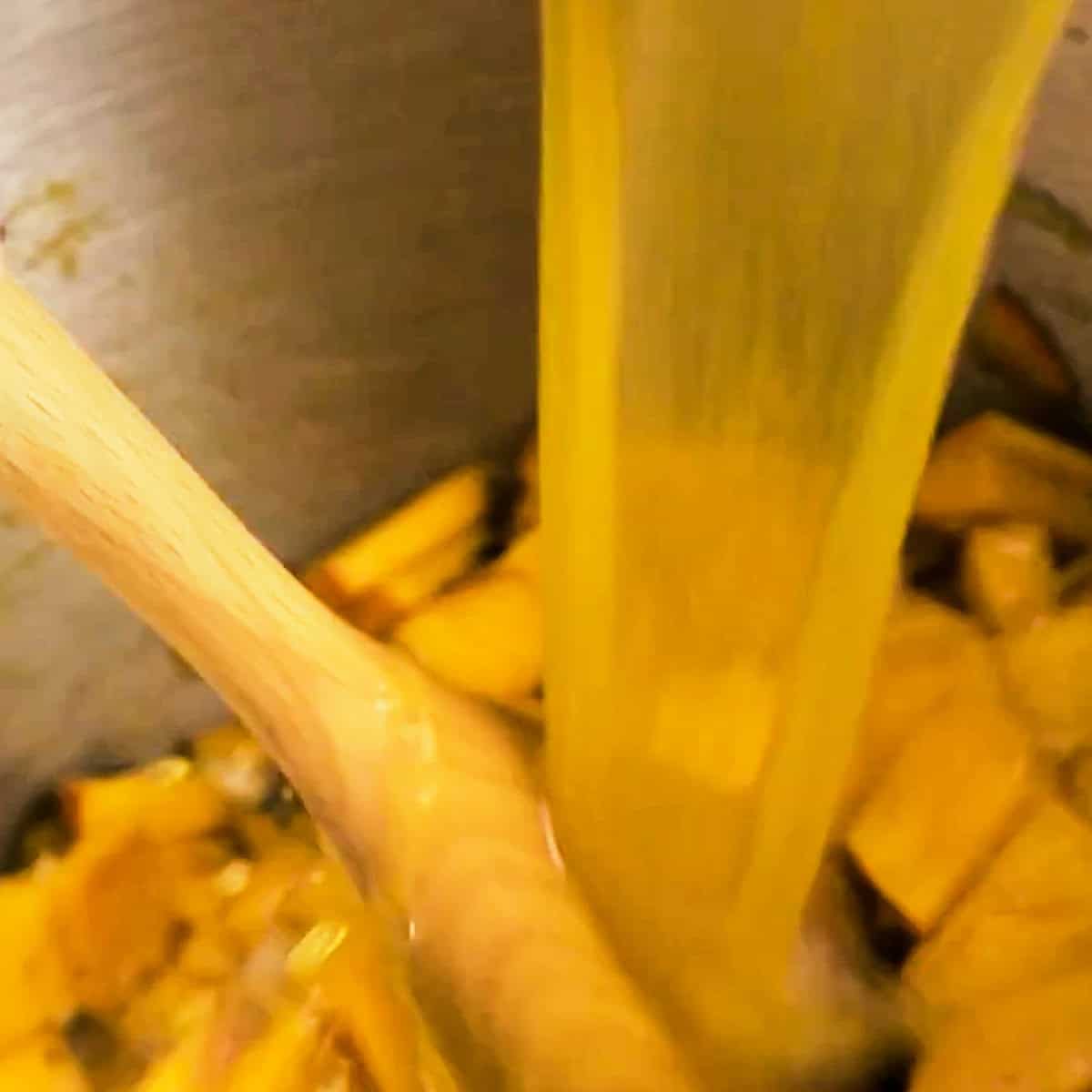 Adding pumpkin stock to cooked pumpkin and onions.
