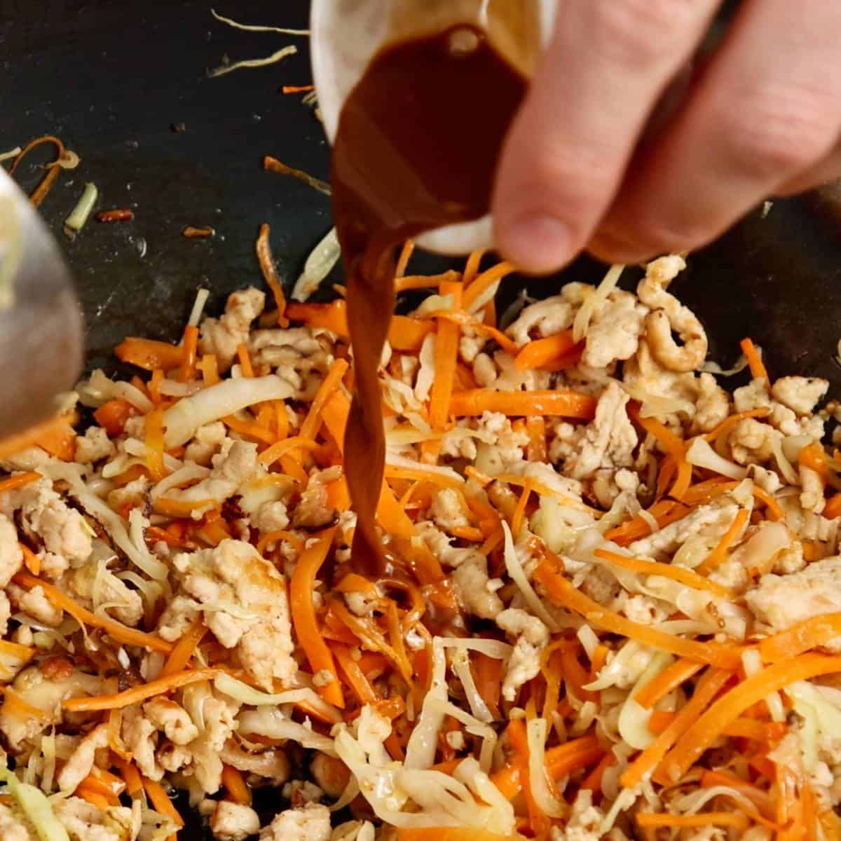 Adding soy sauce to spring roll filling.