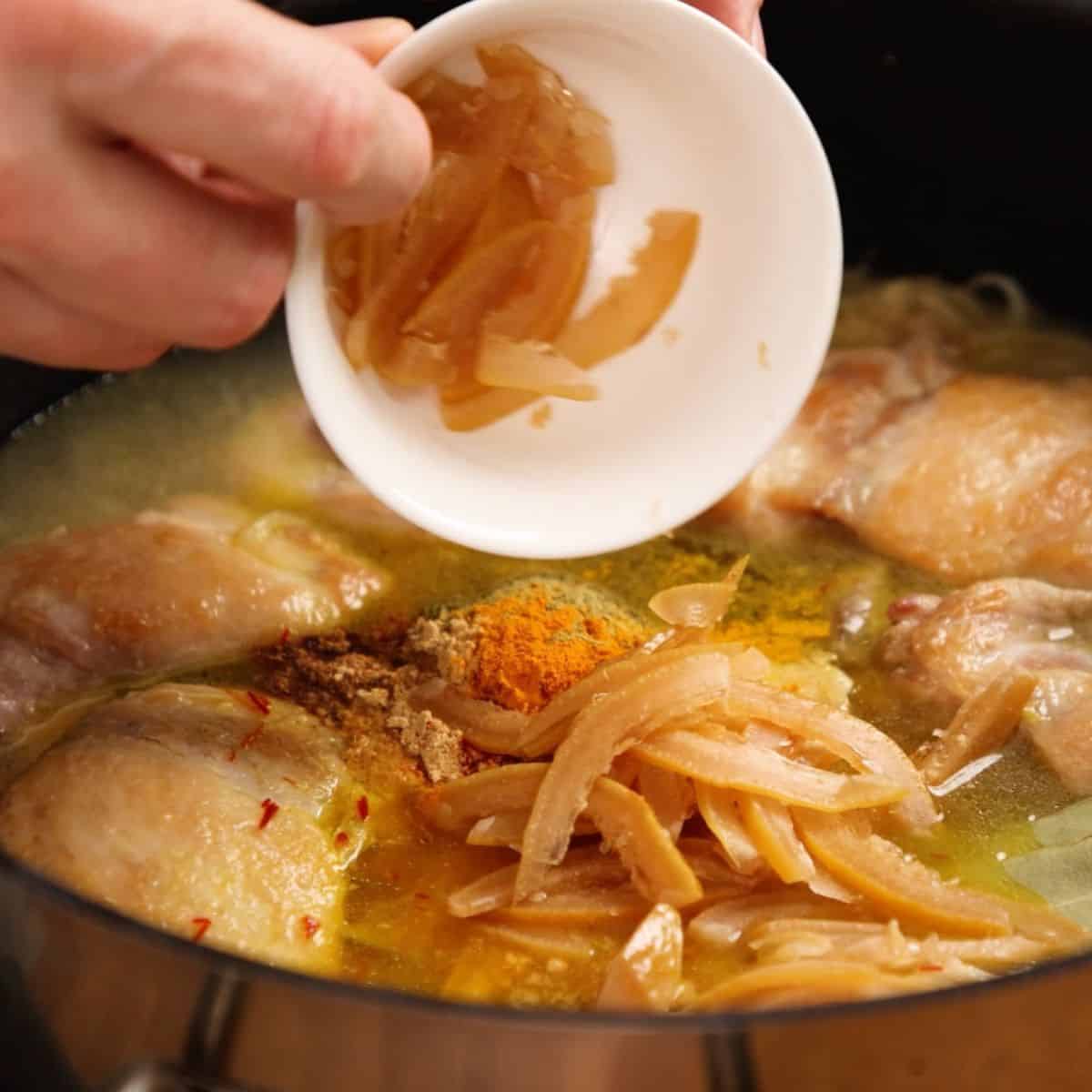 Adding spices and preserved lemon to chicken.