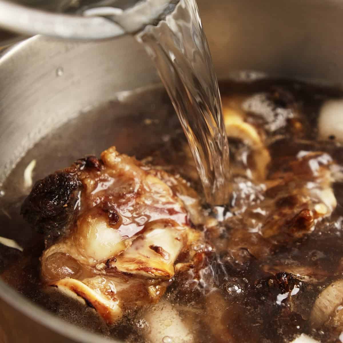 Adding water to ingredients for making beef stock.