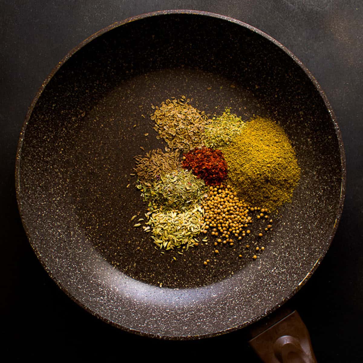 Spices toasting in a pan.