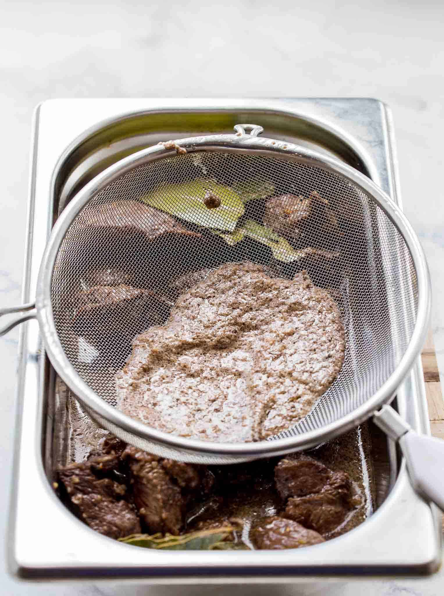 Straining sauce through sieve.
