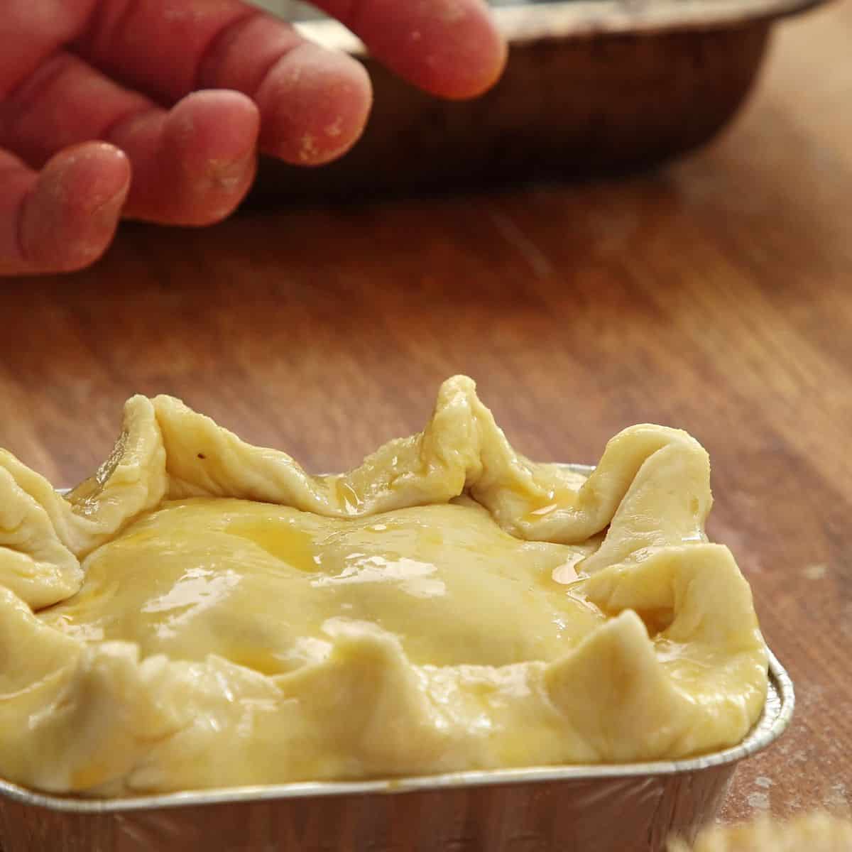 Assembled pies brushed all over with golden egg wash showing glossy surface