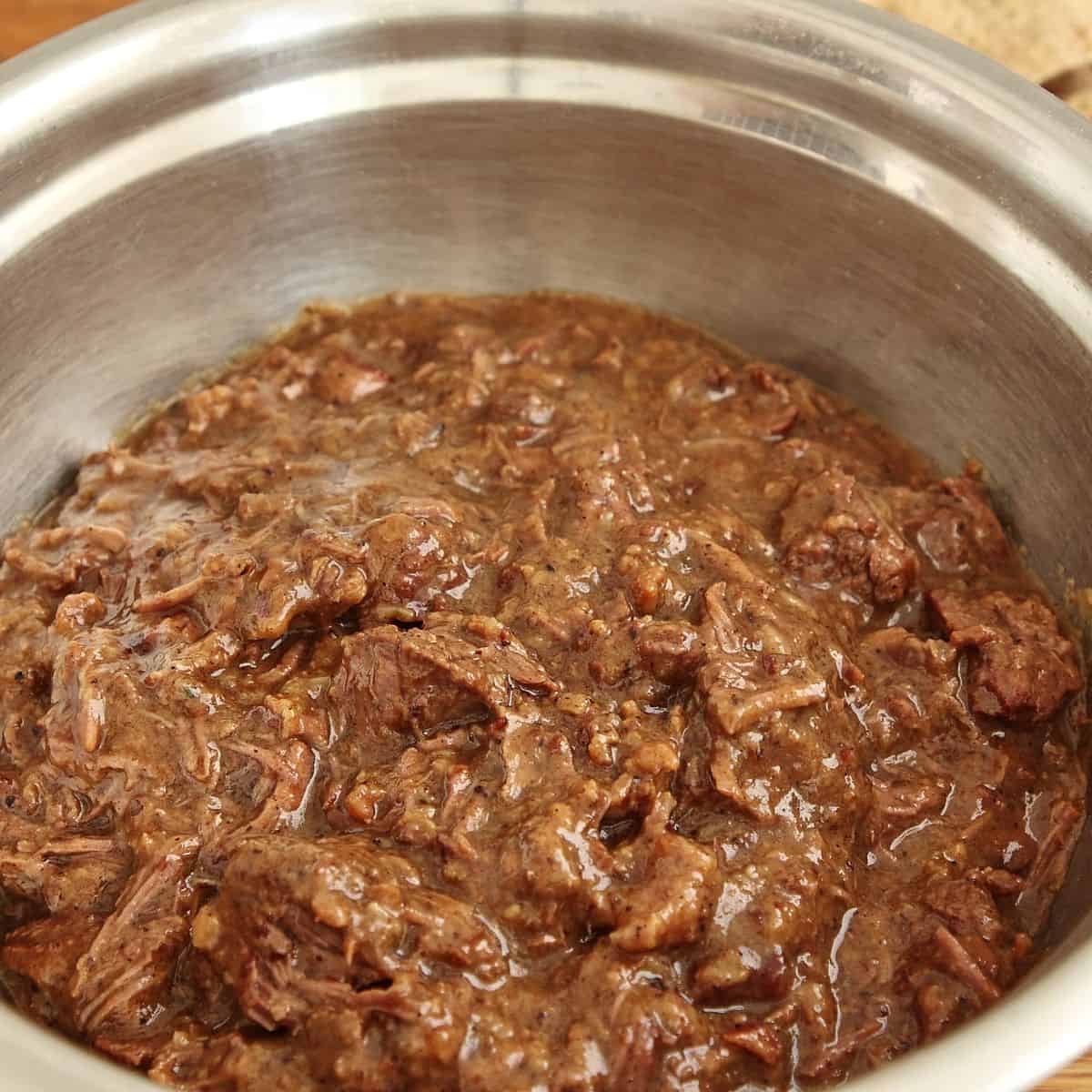 Beef filling transferred to shallow container covered with parchment paper ready for fridge