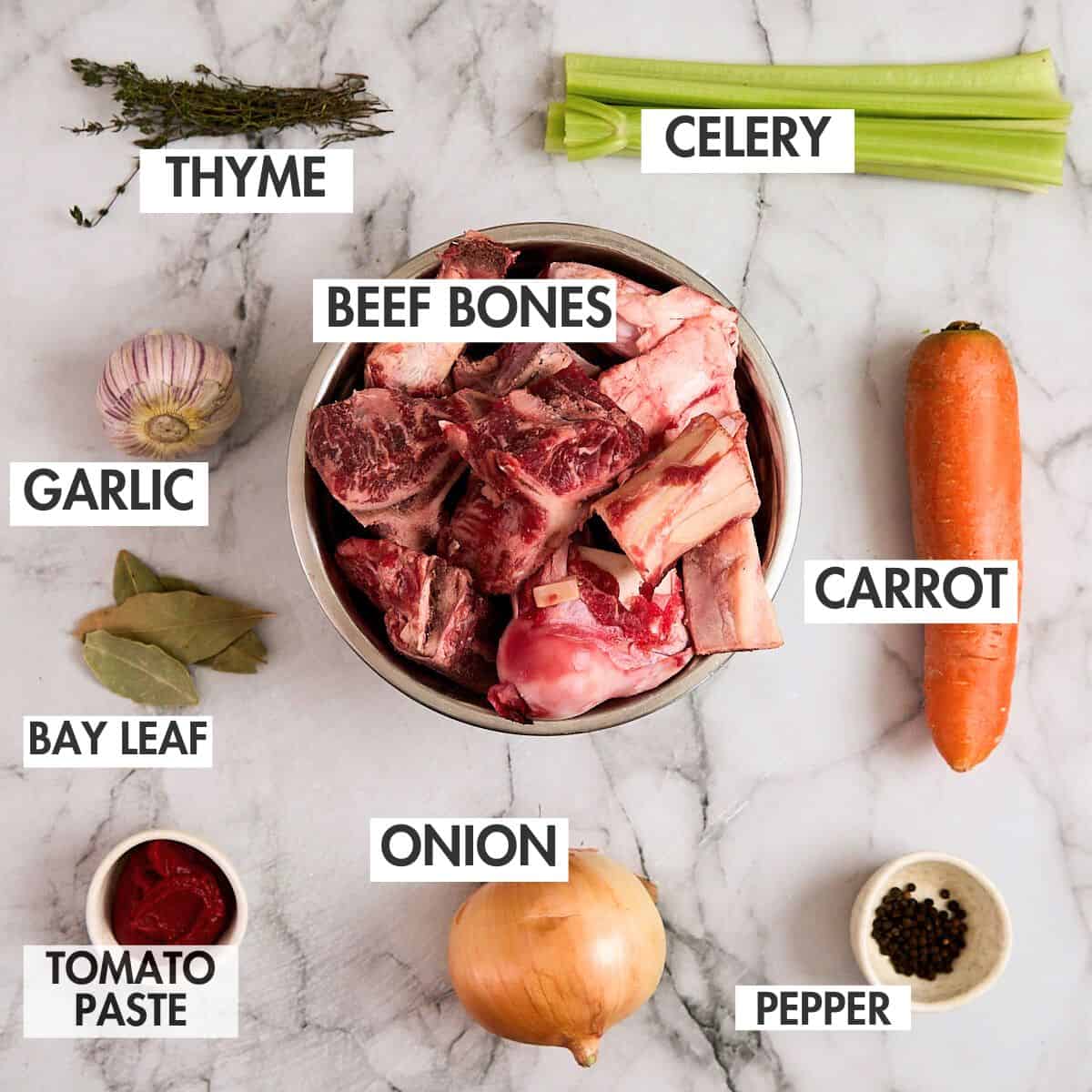 Ingredients for homemade beef stock on a marbled surface.