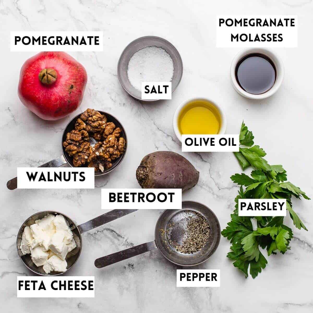 ingredients on a marble board. pomegranate, beet,ssalt, oil, molasses,herbs,cheese,nuts