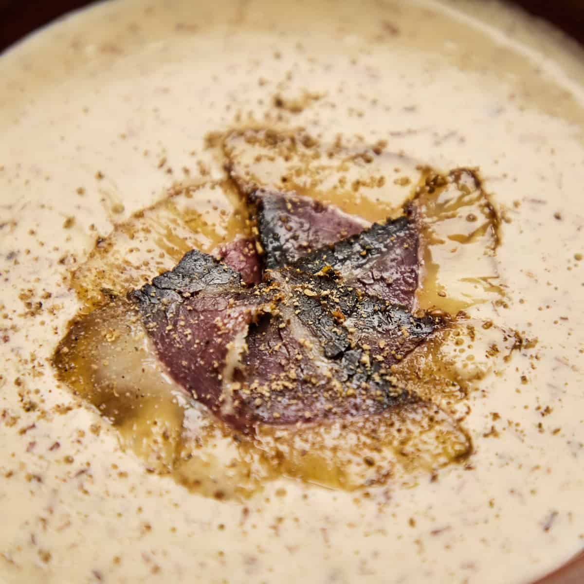 Biltong pieces nestled in creamy soup base with visible spice speckling.