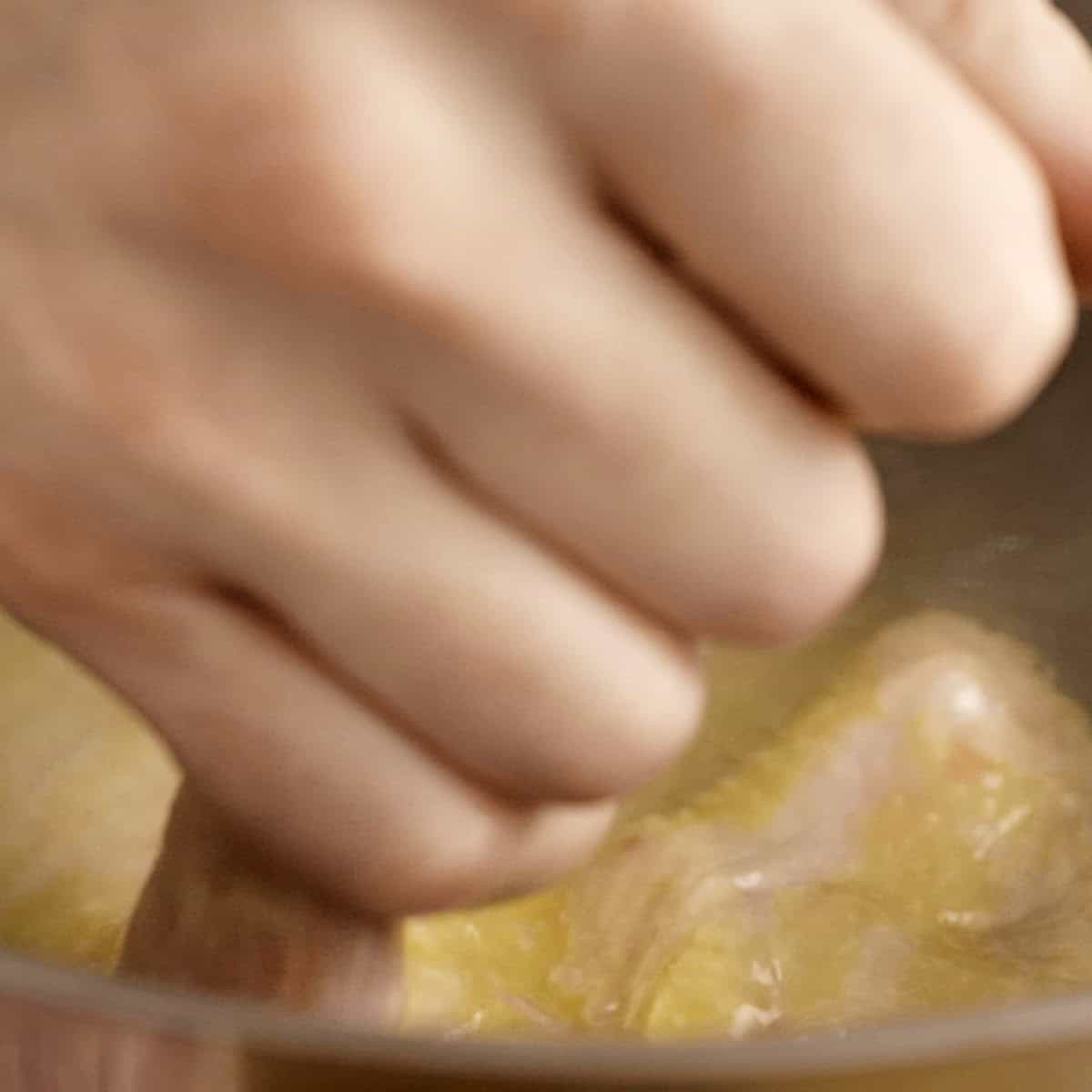 Dipping chicken into hot water to blanche it.