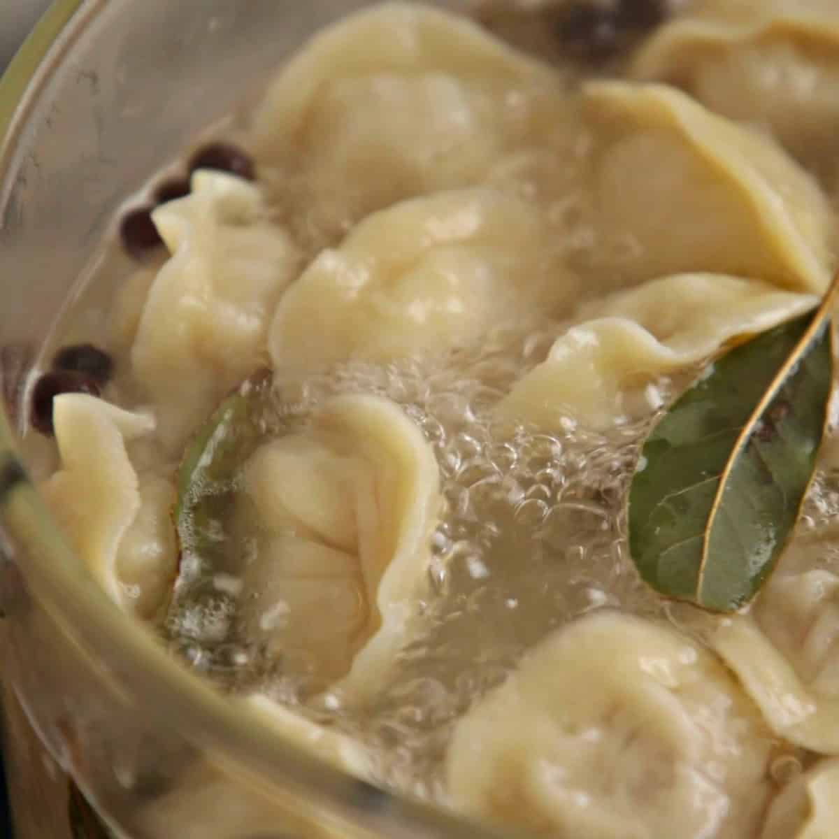 Boiling pelmeni in water with bay leaf and all spice.