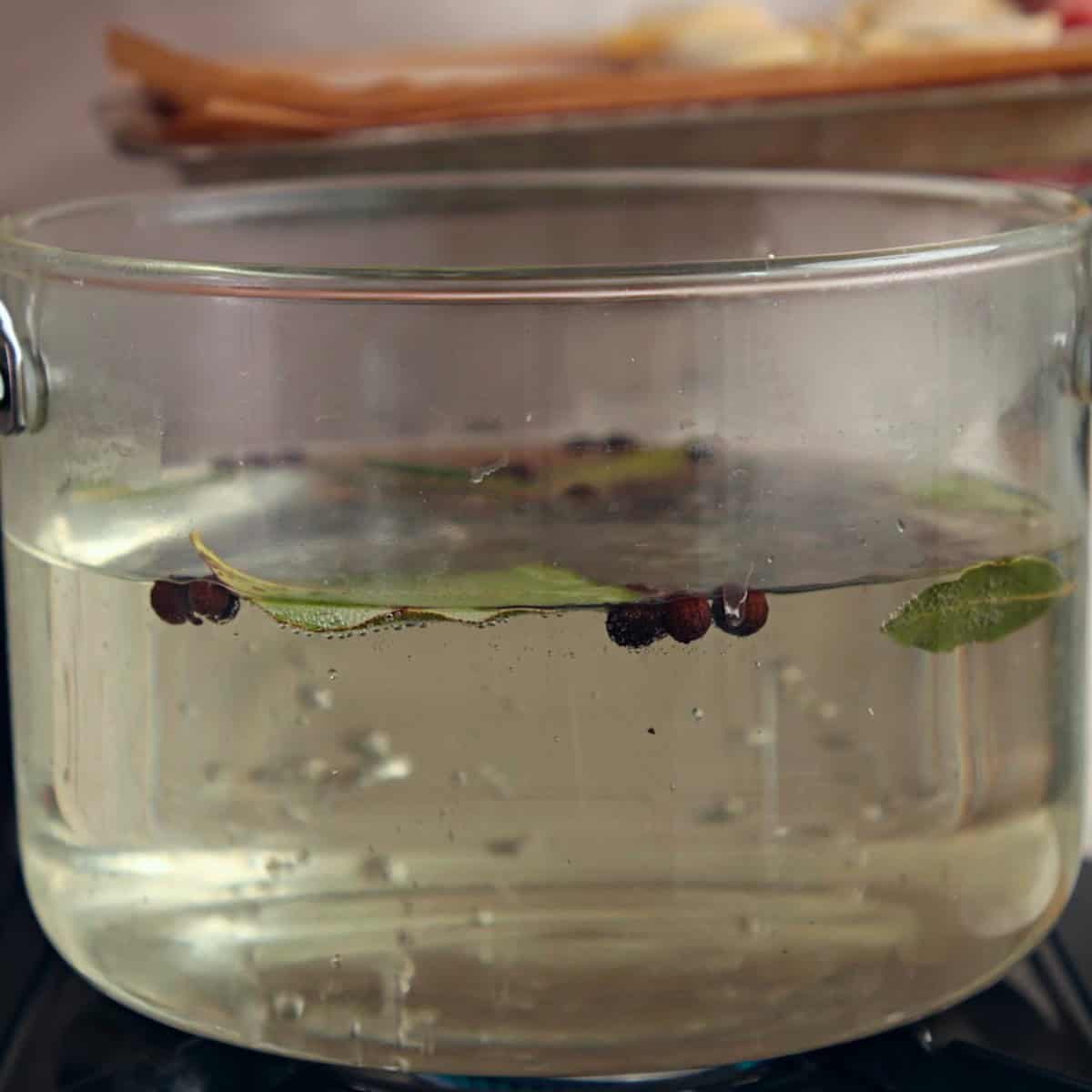 Water in a clear pot with herbs and spices.
