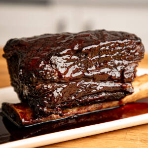Braised beef short ribs with bbq glaze and red wine sauce on a white plate.