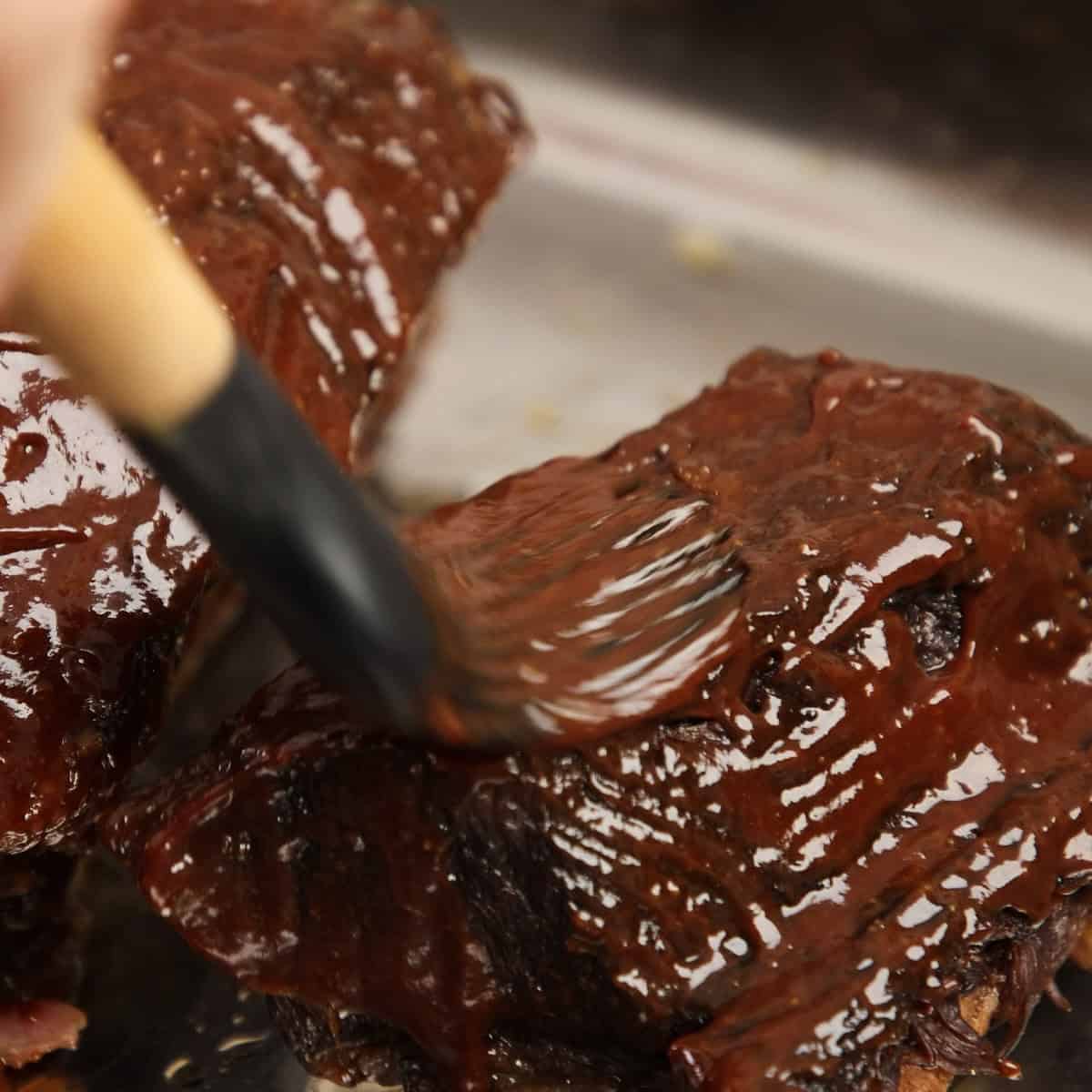 Brushing cooked beef with barbecue sauce glaze.