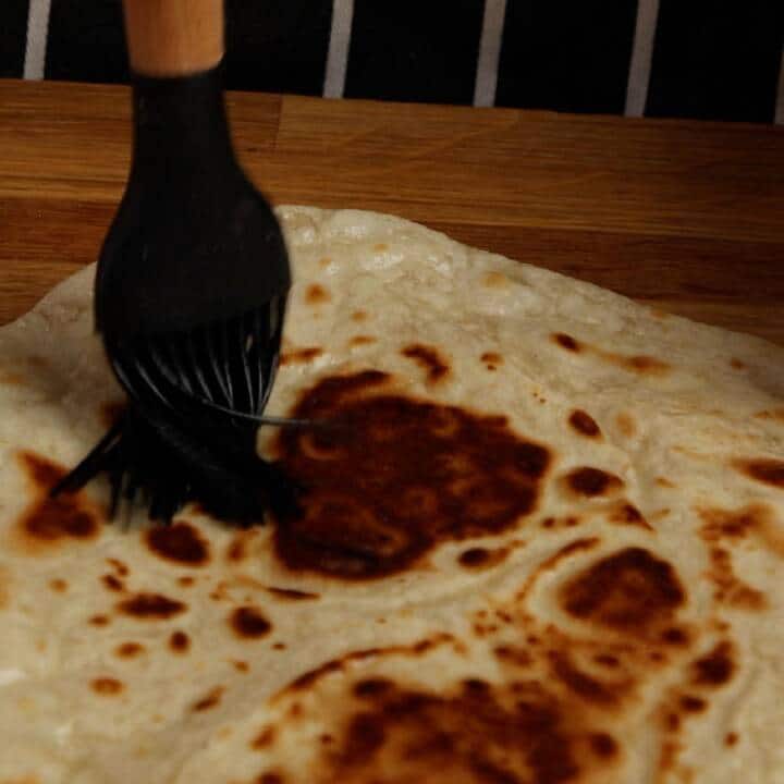Brushing flatbread with melted ghee.