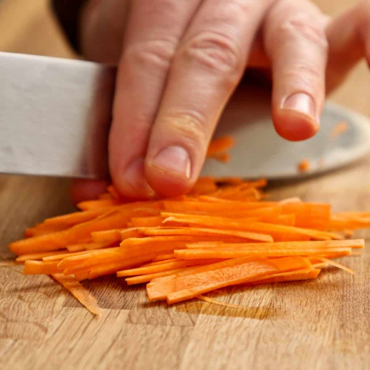 Thinly sliced carrots on wooden board.