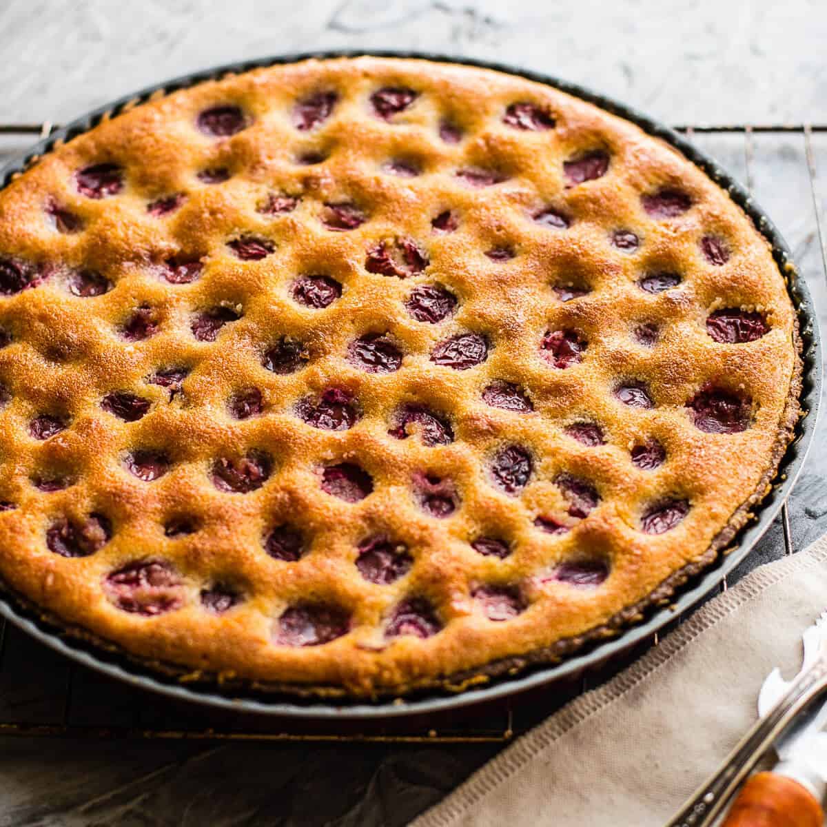 Whole baked cherry tart in tart mould.