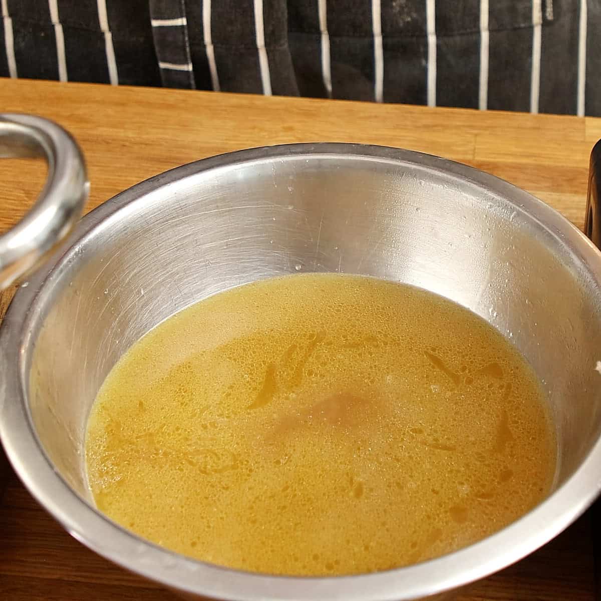 Reduced, concentrated chicken stock in a stainless steel pot.