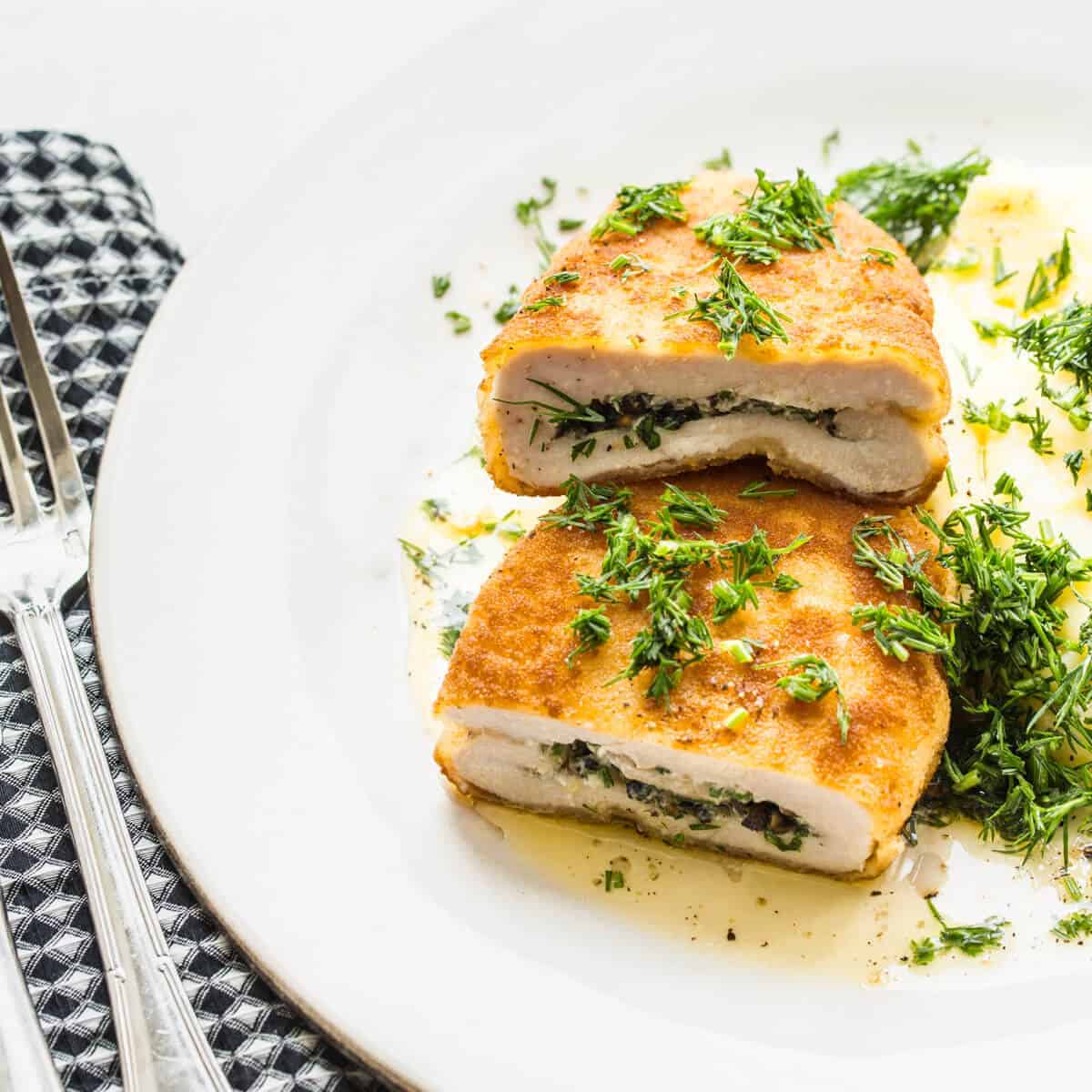 chicken kiev with mashed potatoes and dill on a white plate