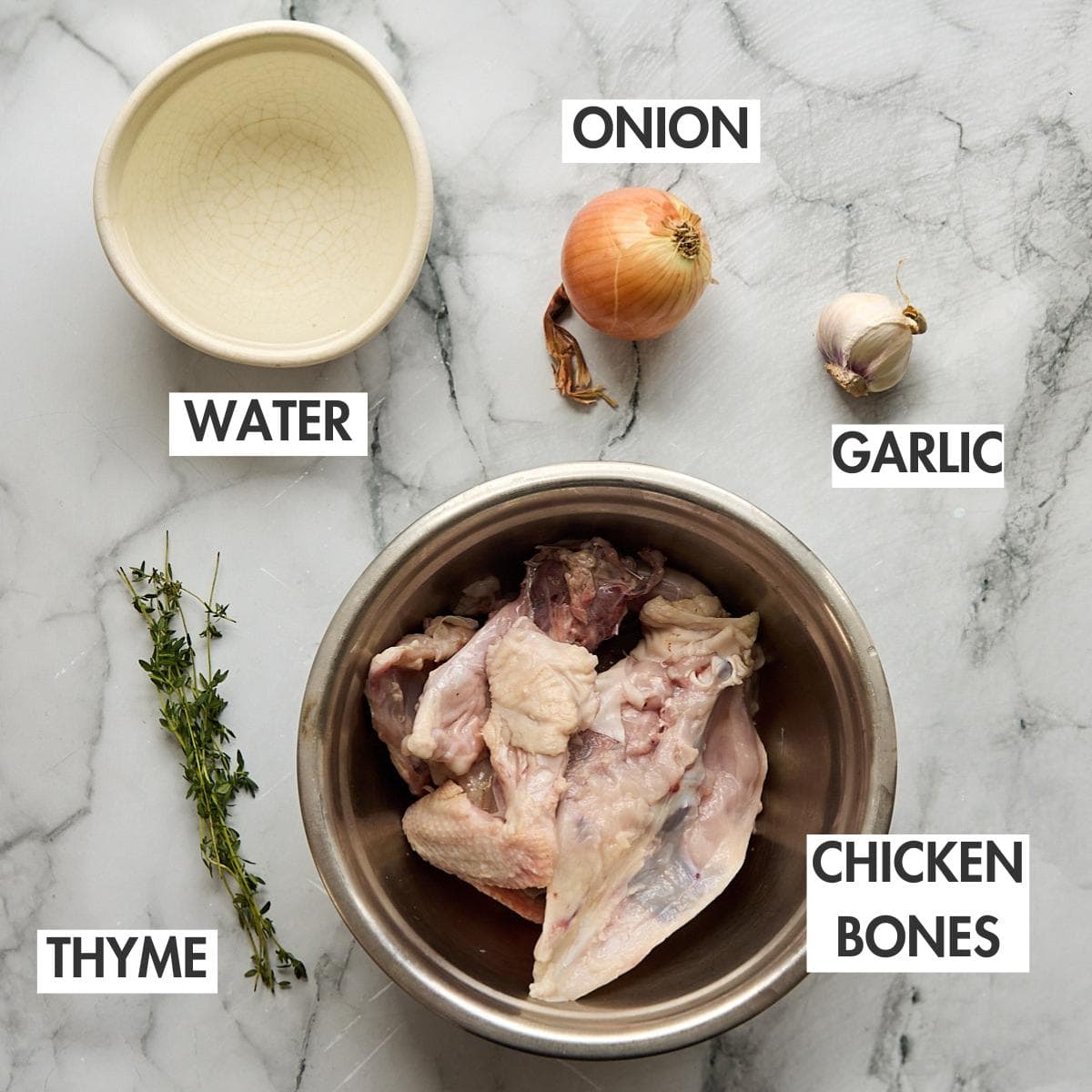 Ingredients for making chicken stock on a marbled background.