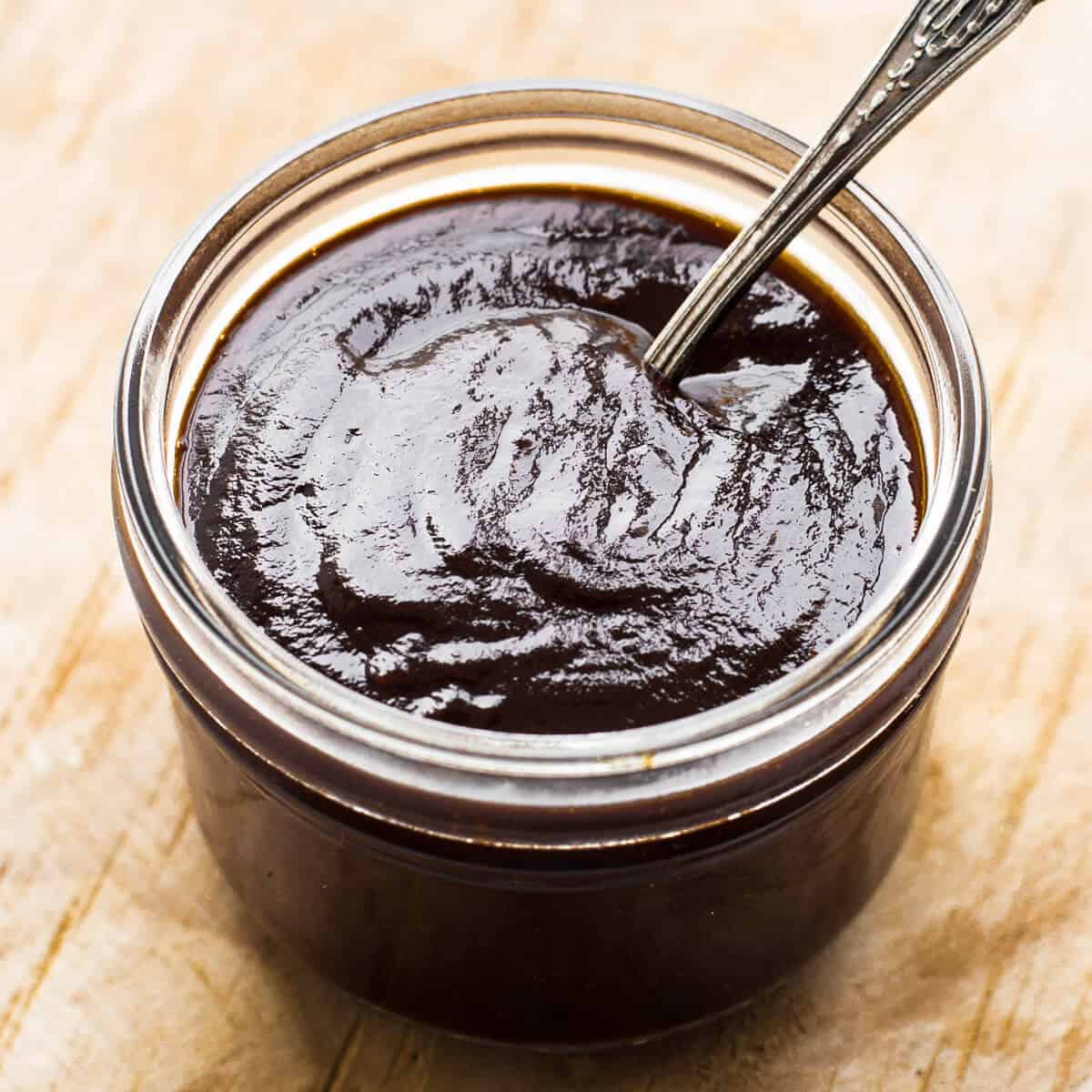 Kilner jar of chocolate bbq sauce on a wooden board.