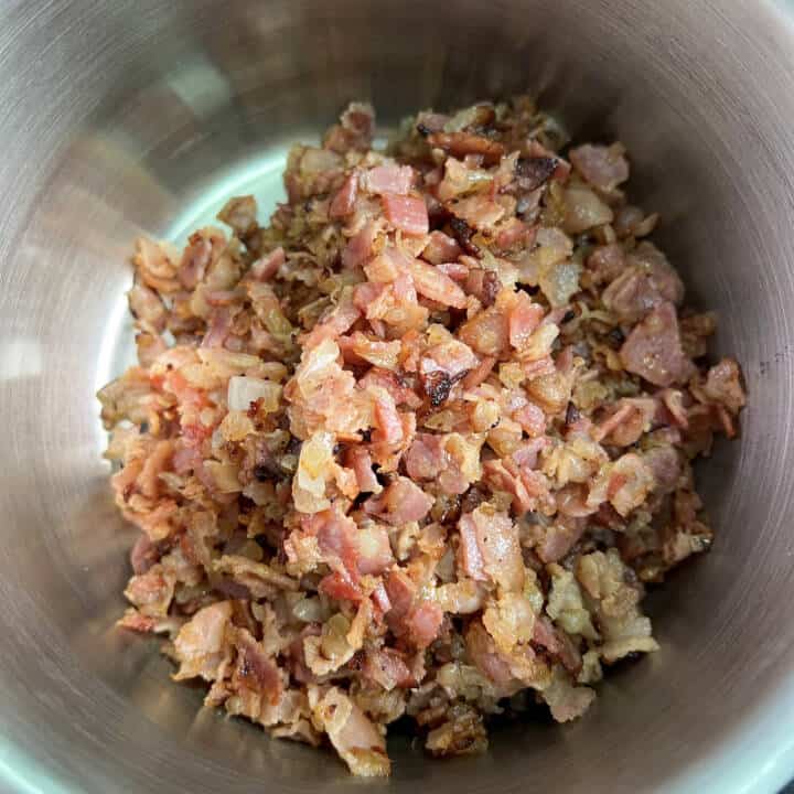 Fried bacon and onions in a sauce pan.