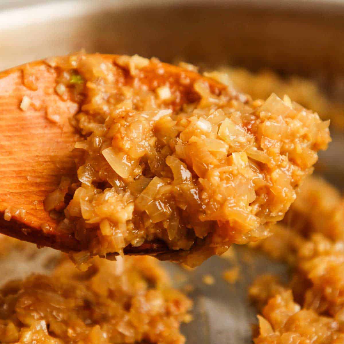 Cooked aromatics on a wooden spoon.