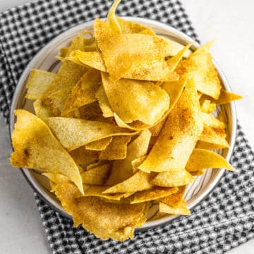 corn tortilla chips on a beige plate and black checkered napkin
