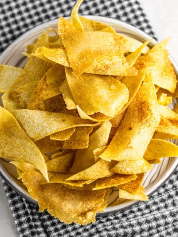 corn tortilla chips on a beige plate and black checkered napkin