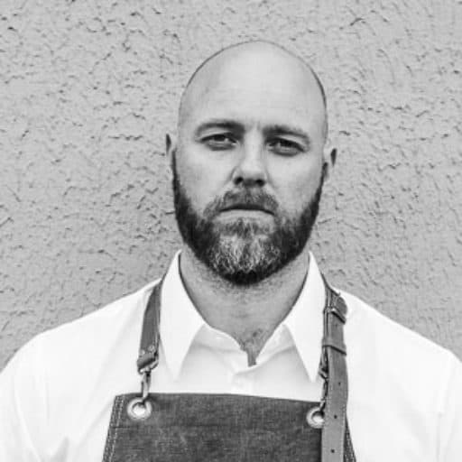 black and white picture of chef standing against wall