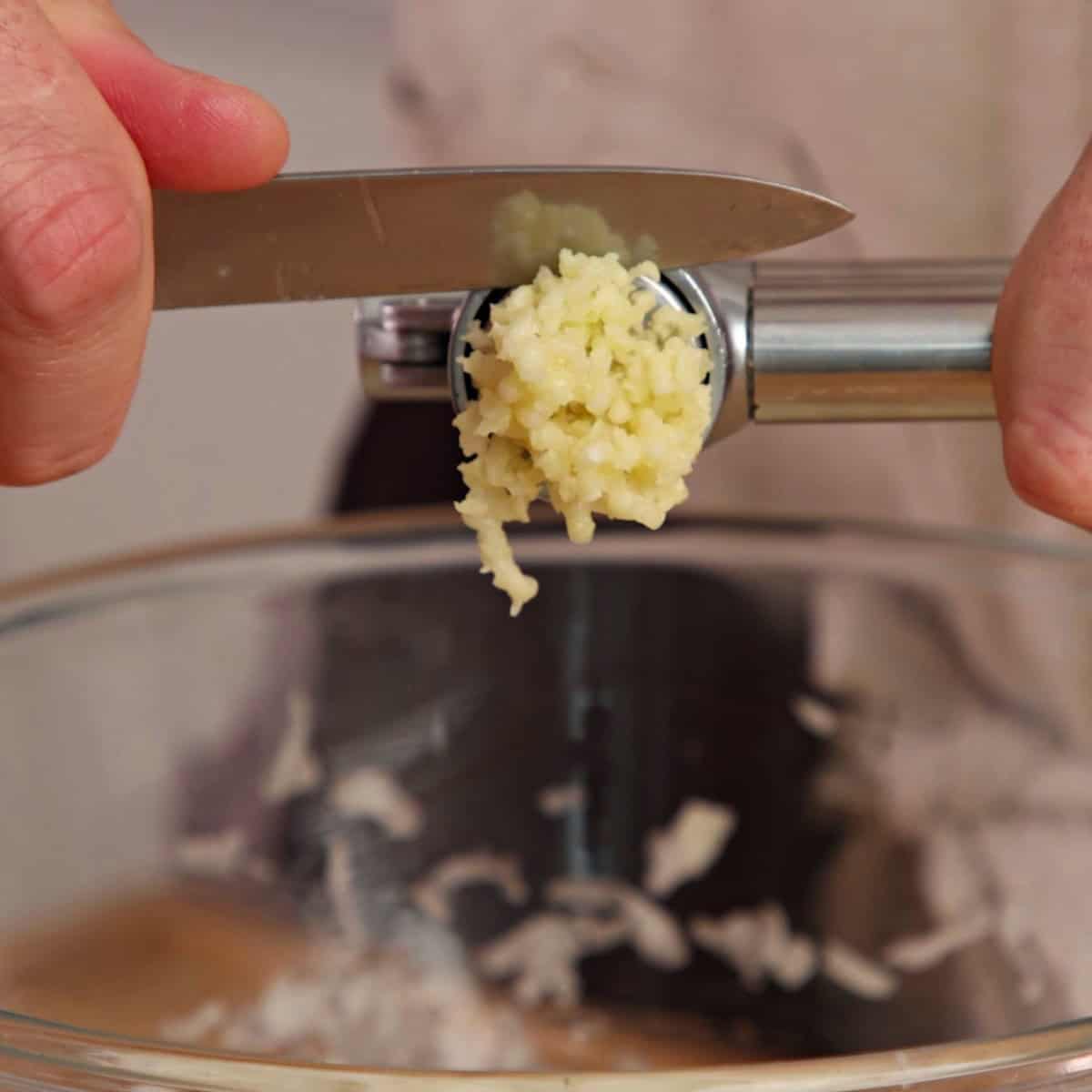 Crushing garlic in a garlic crush.