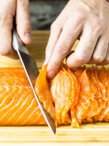 Slicing salmon gravlax on a wooden board.