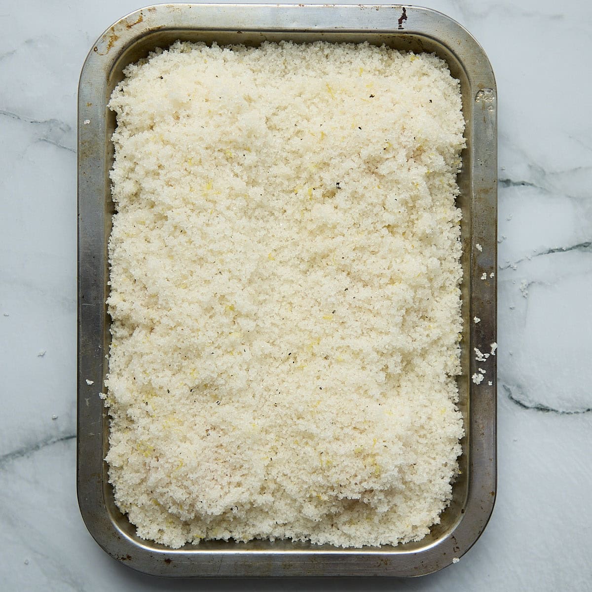 Salt cure mixture covering egg yolks on tray.