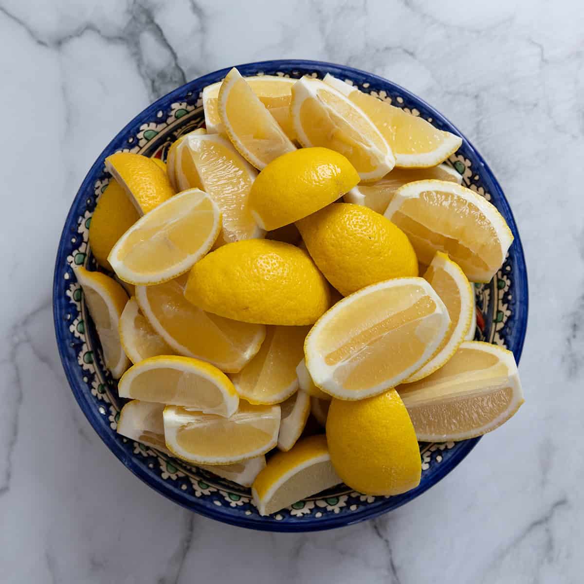 Cut lemon wedges in a blue bowl.