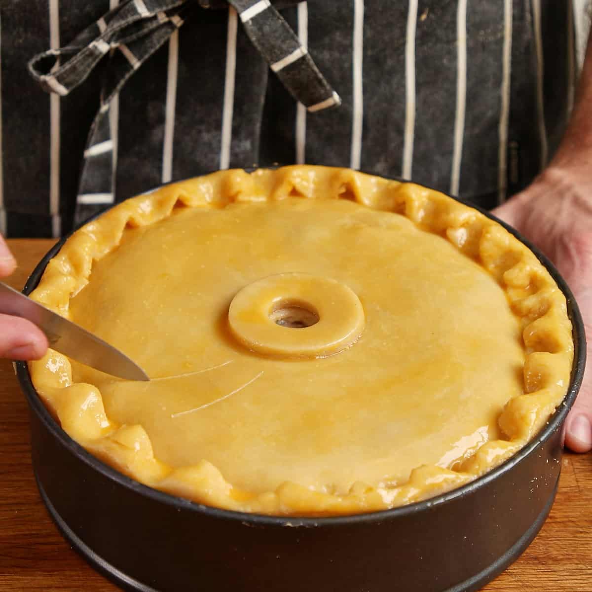 Unbaked chicken pie with a crimped edge and central steam vent.