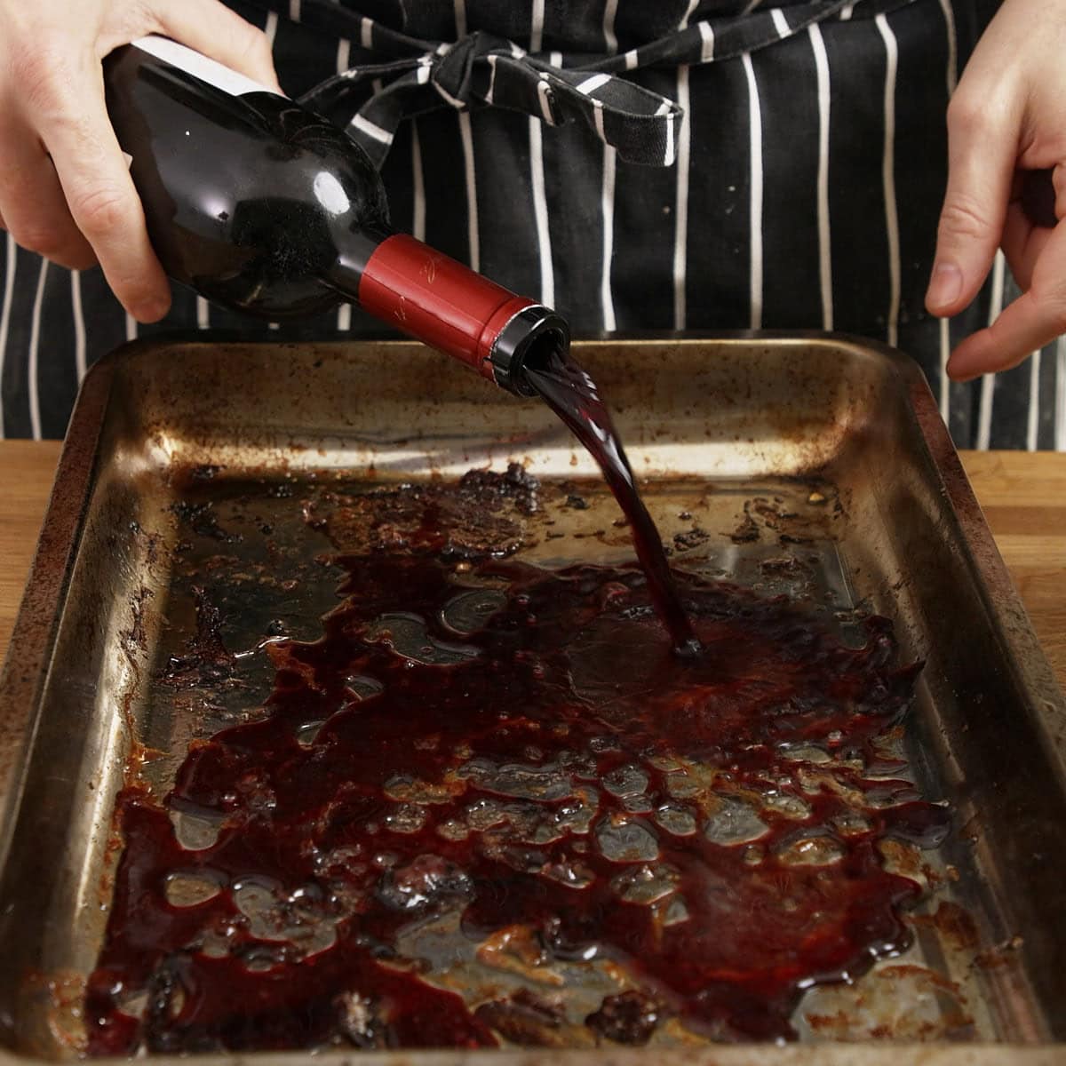 Deglazing beef bone roasting tray with red wine to get fond for beef stock.