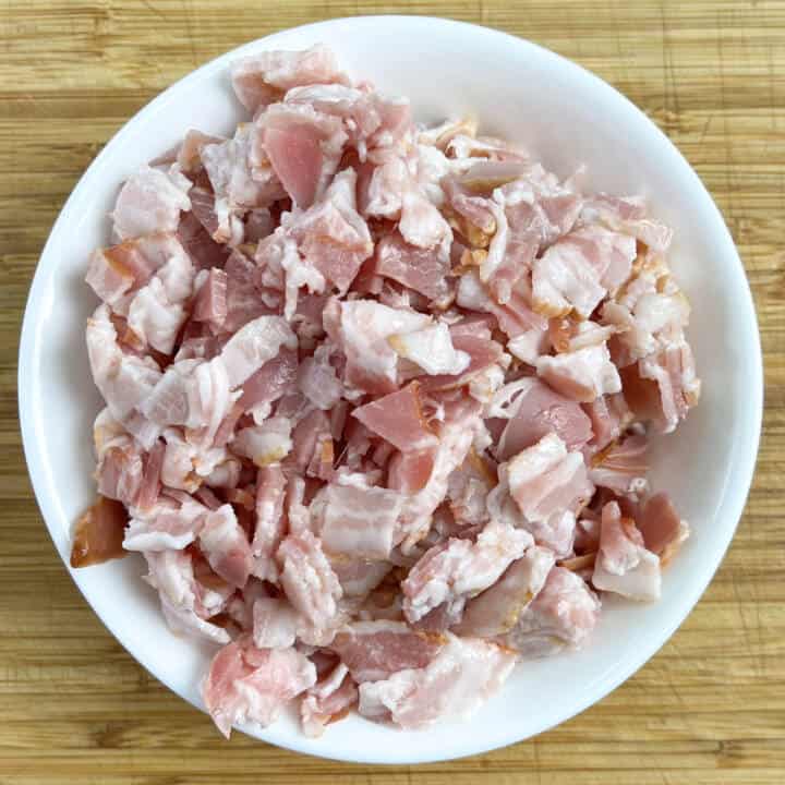 Diced streaky bacon in a white bowl.