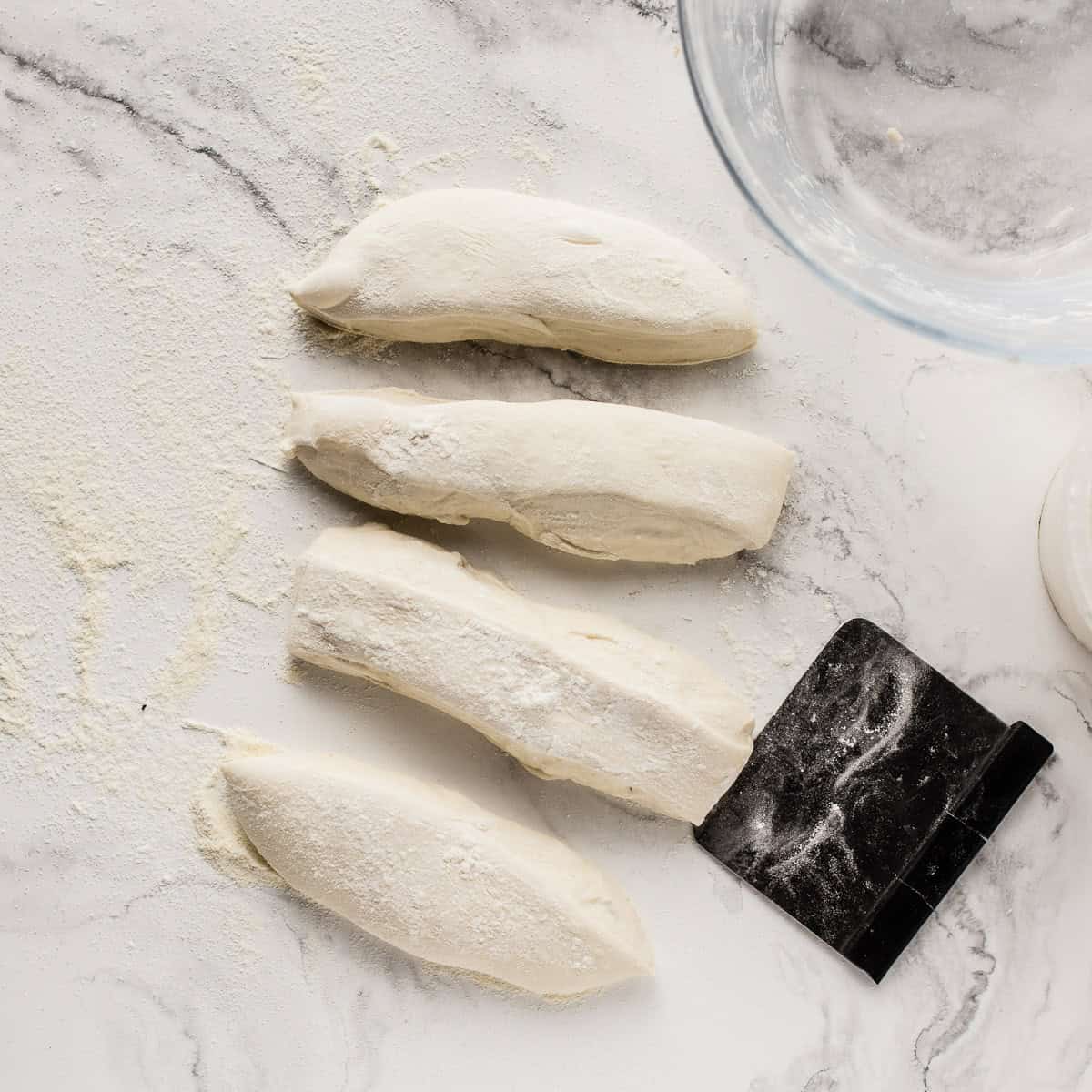 Divided baguette dough on a marble surface.