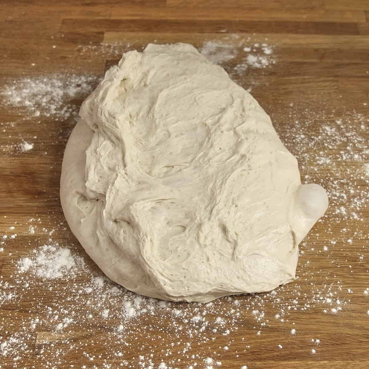 Proven sourdough on a floured wooden table.